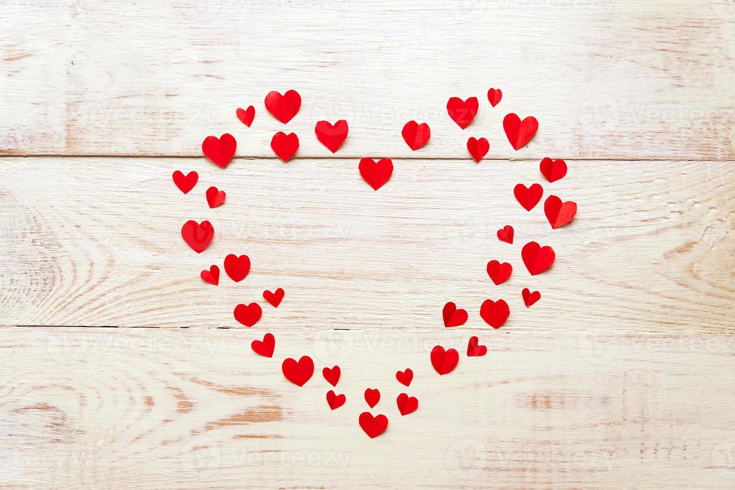 stort rött hjärta av utskuret papper små hjärtan på träbakgrund. handgjord dekoration för alla hjärtans dag. foto
