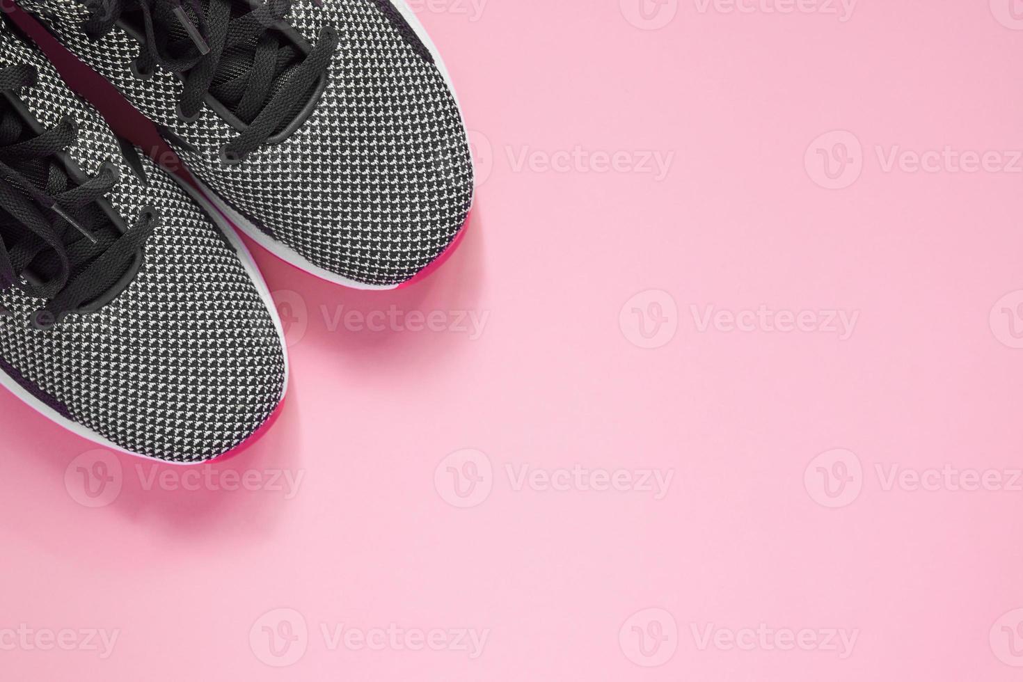 sportsko på rosa bakgrund. svarta och vita kvinnliga sneakers för träning. livsstilskoncept med kopia utrymme. toppvy foto