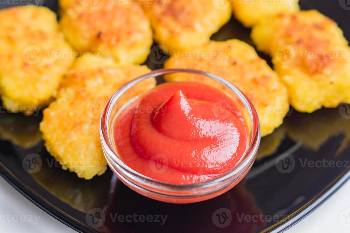 stekt crispy chicken nuggets med ketchup på svart tallrik. ohälsosam mat. foto
