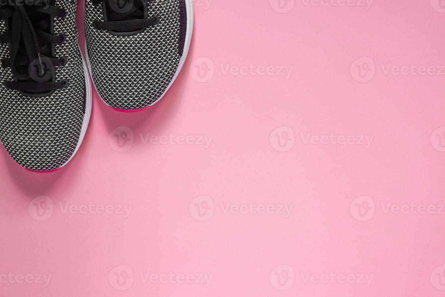 sportsko på rosa bakgrund. svarta och vita kvinnliga sneakers för träning. livsstilskoncept med kopia utrymme. toppvy foto