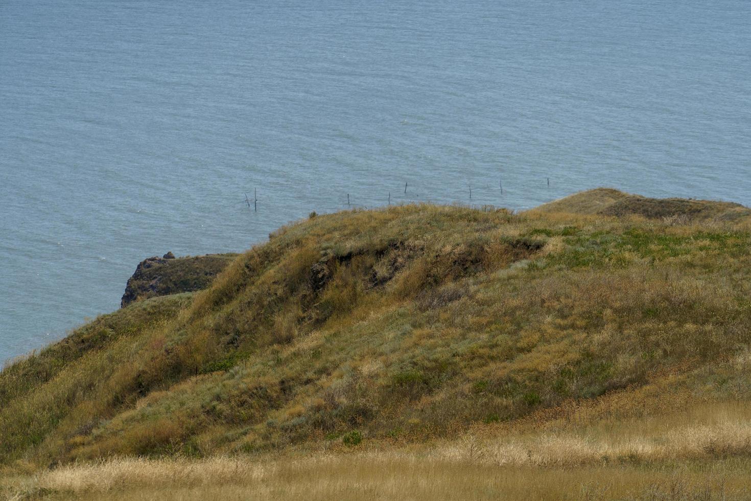 havslandskap med utsikt över kullar med torrt gräs foto