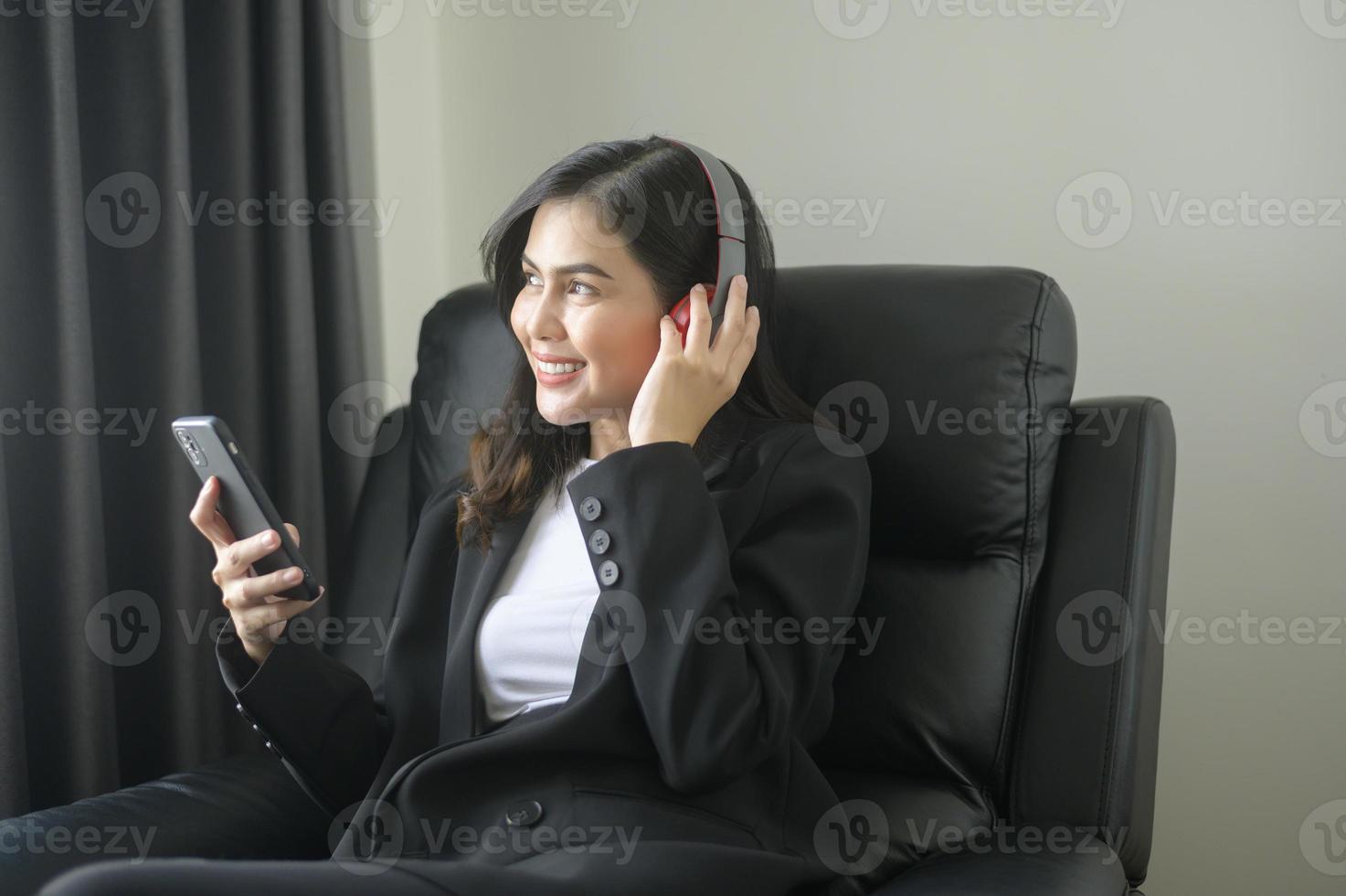 ung avkopplande affärskvinna som använder smartphone och lyssnar på musik i moderna kontor. foto