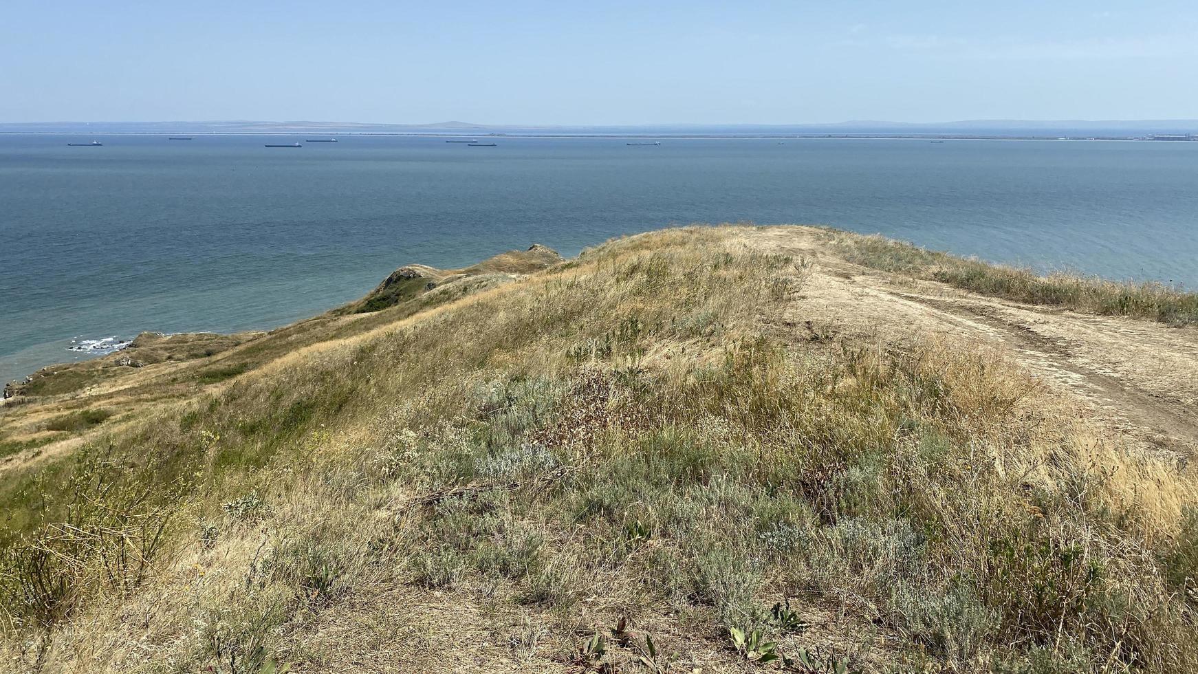 havslandskap med utsikt över kullar med torrt gräs foto