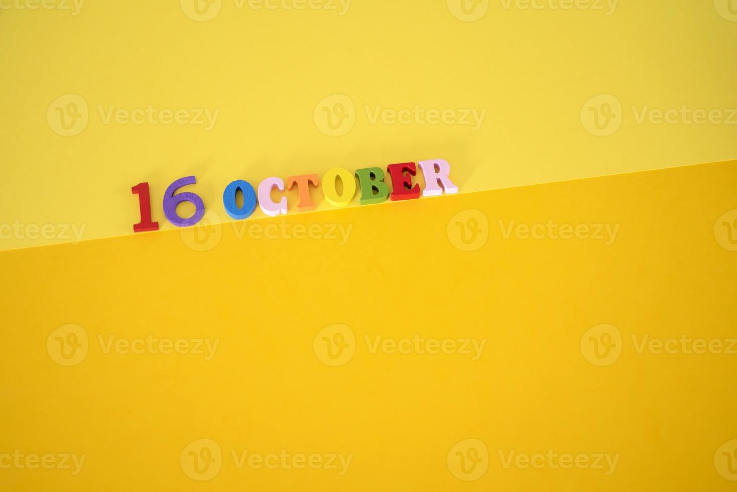 16 oktober på en gul, papper bakgrund med trä- och flerfärgad brev med Plats för text. foto