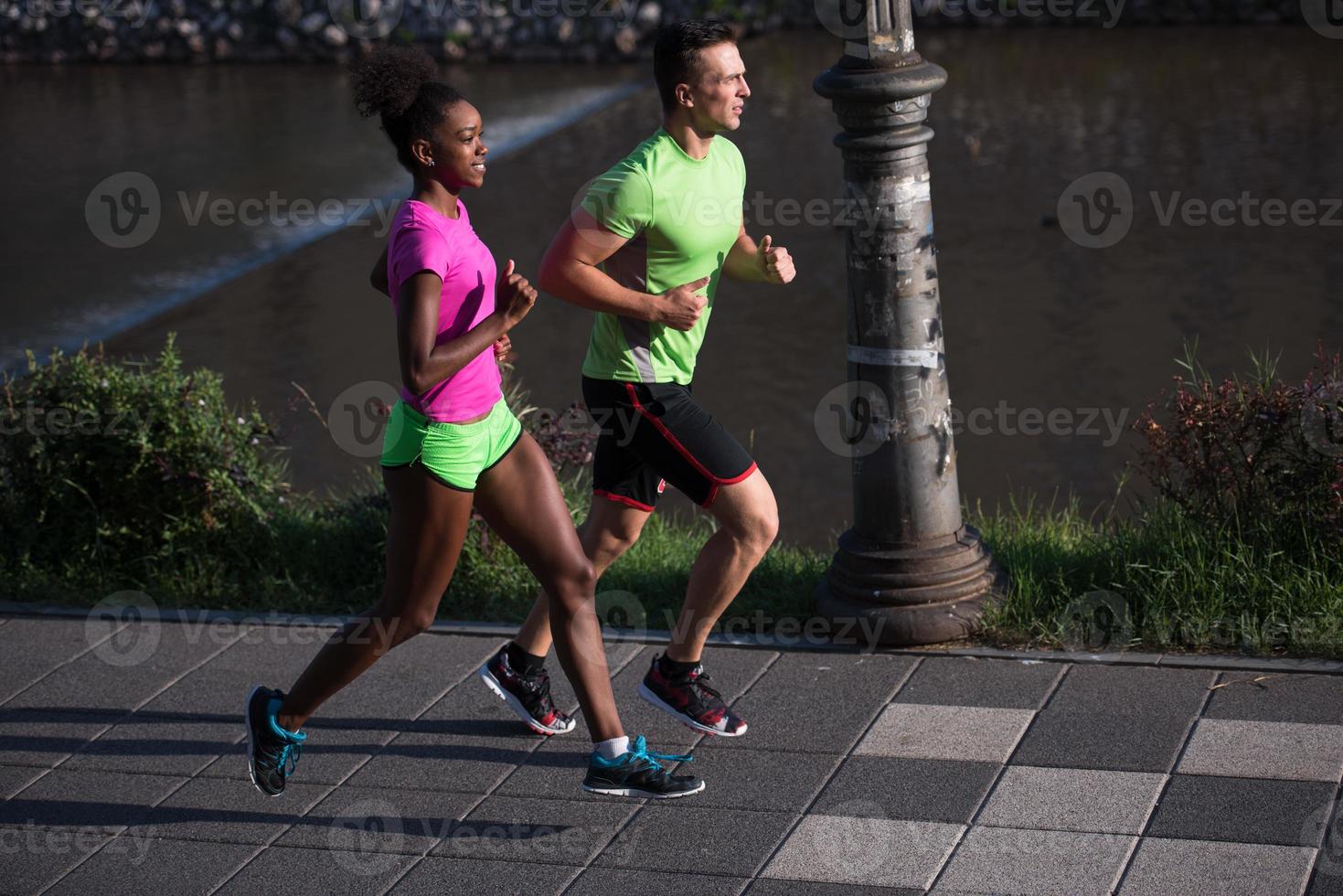 ung leende multietnisk par joggning i de stad foto