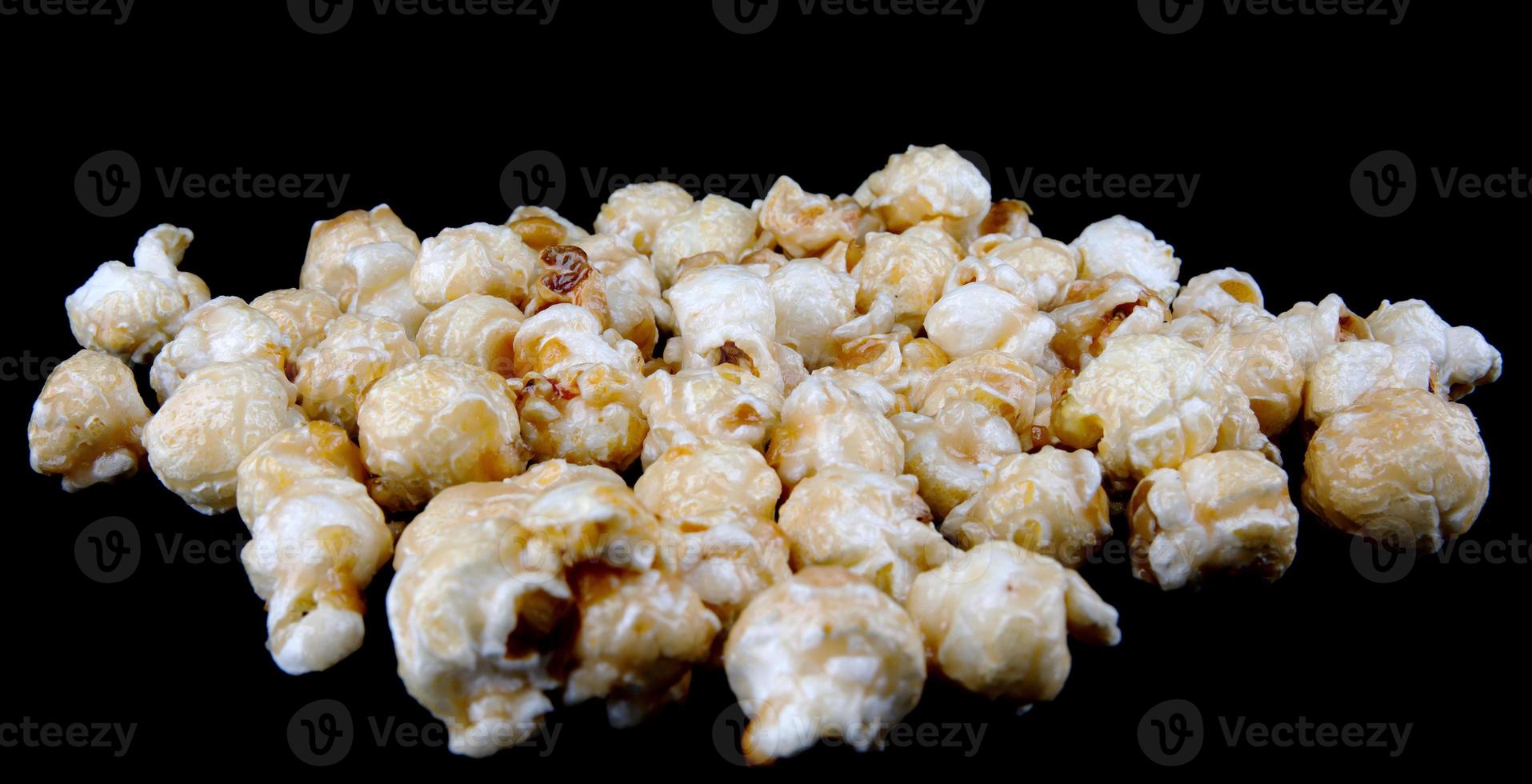 Krispig popcorn på en svart bakgrund. popcorn i kola glasyr. foto