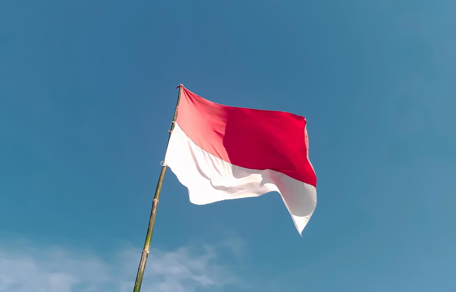 indonesiska flagga med en bambu Pol flygande hög i de himmel. indonesiska oberoende dag augusti 17:e foto