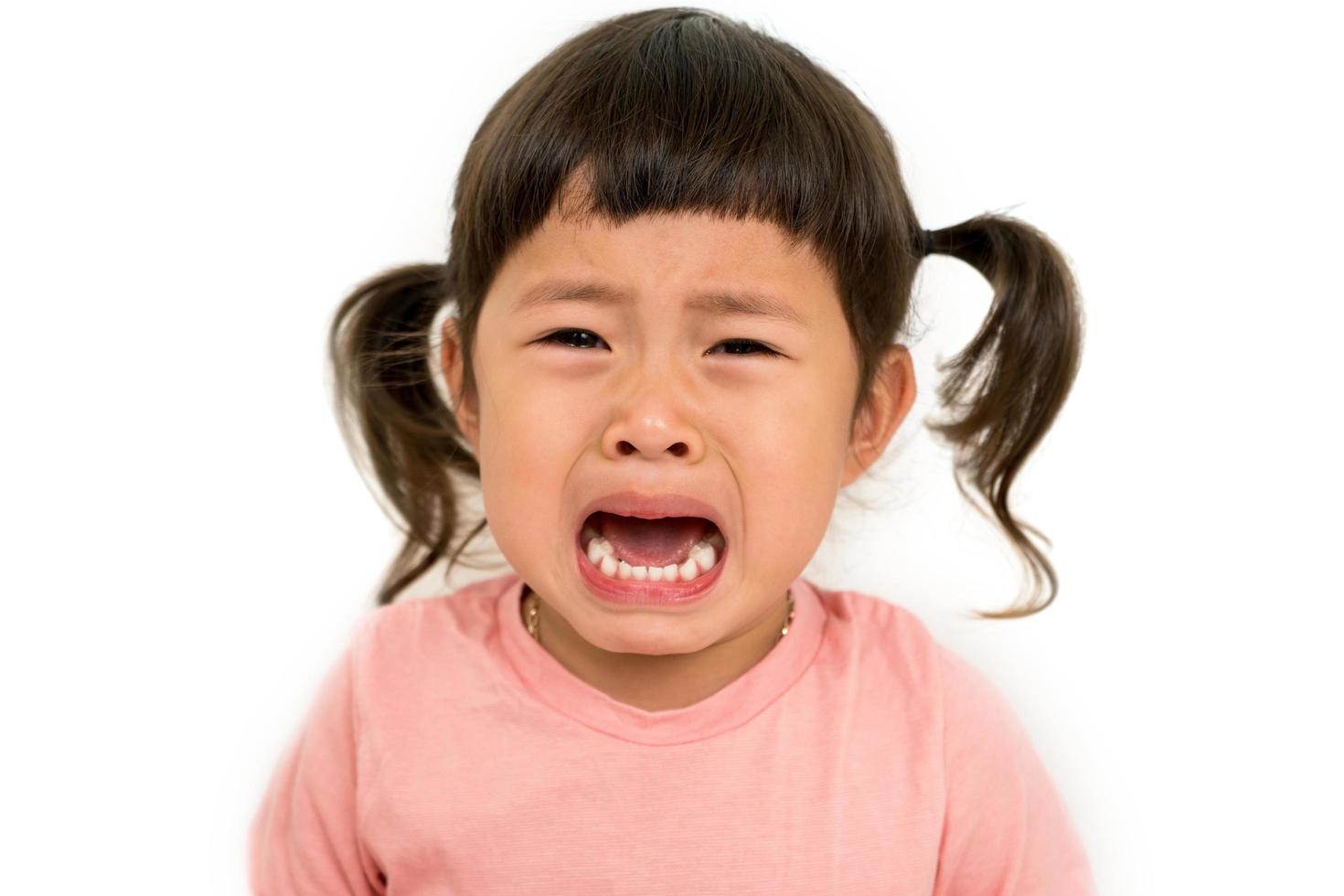 liten asiatisk flicka gråta på vit bakgrund foto