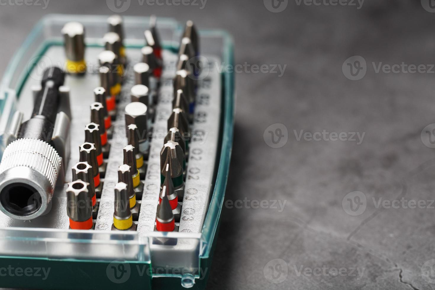 en uppsättning av annorlunda bitar för skruvmejslar och reparationer i en låda på en grå bakgrund foto