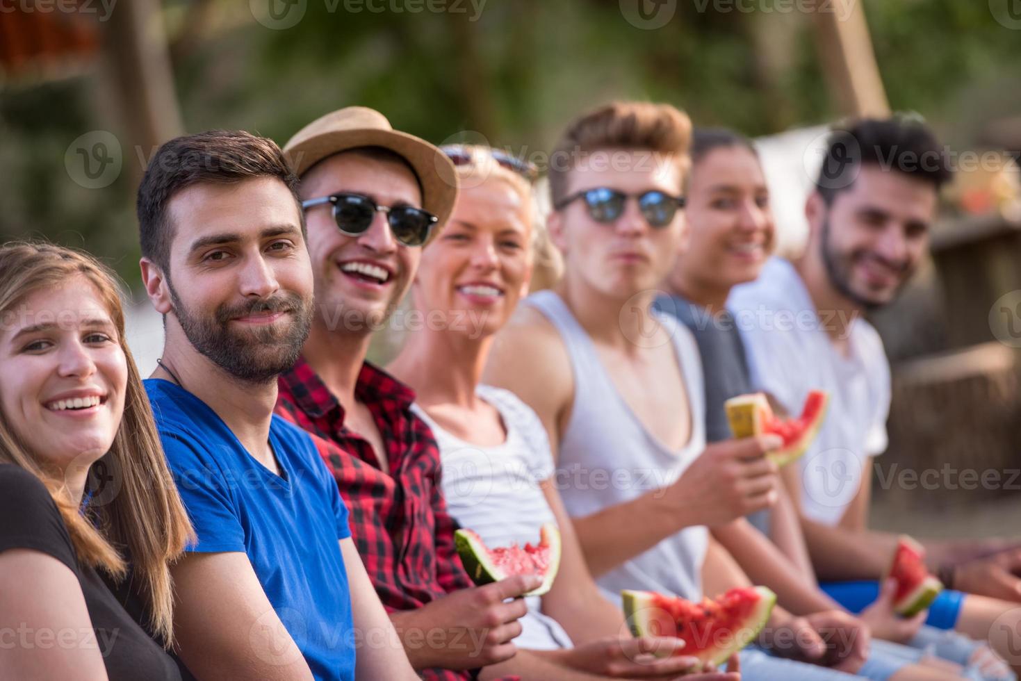 vänner njuter vattenmelon medan Sammanträde på de trä- bro foto