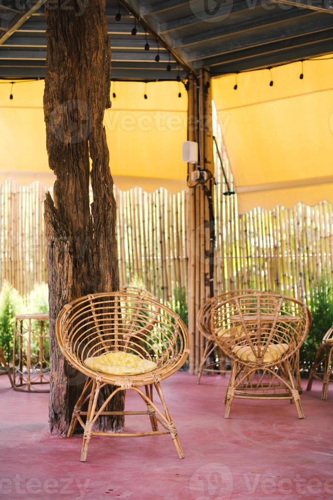 korg- rotting hängande stol i Kafé, natur se. rotting vardagsrum hängande stol på de balkong med grön natur bakgrund foto