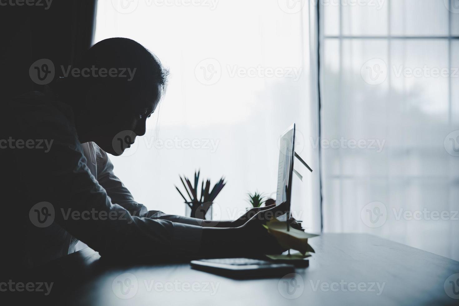 påfrestning företag kvinna person från hård arbete, depression i kontor. trött och angelägen anställd kvinna med olycklig på problem jobb. ung affärskvinna Sammanträde ledsen främre av bärbar dator dator på skrivbord. foto