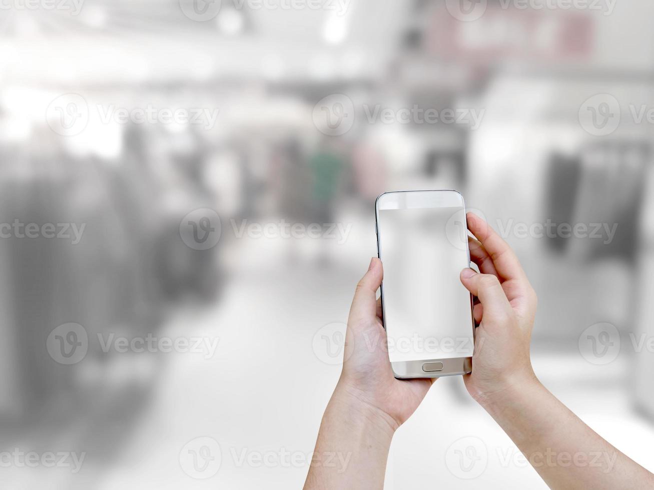 hand som håller mobil smart telefon med köpcentrum suddig bakgrund foto