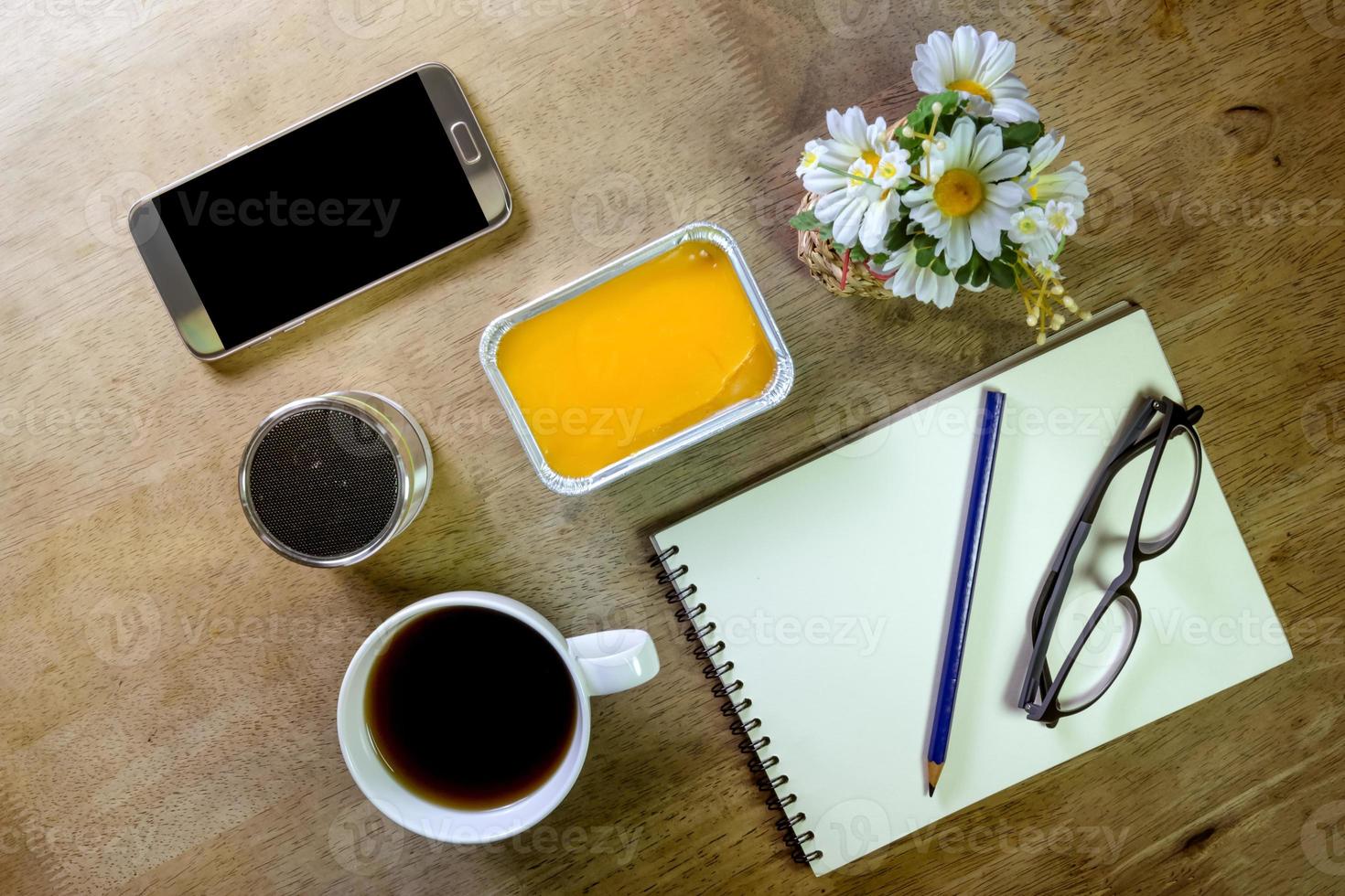 notera bok med kaffe penna högtalare och smartphone på skrivbordet foto