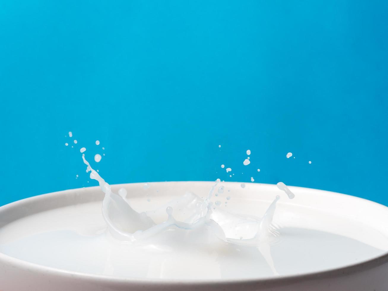 stänk av mjölk från en kopp på blå bakgrund. foto