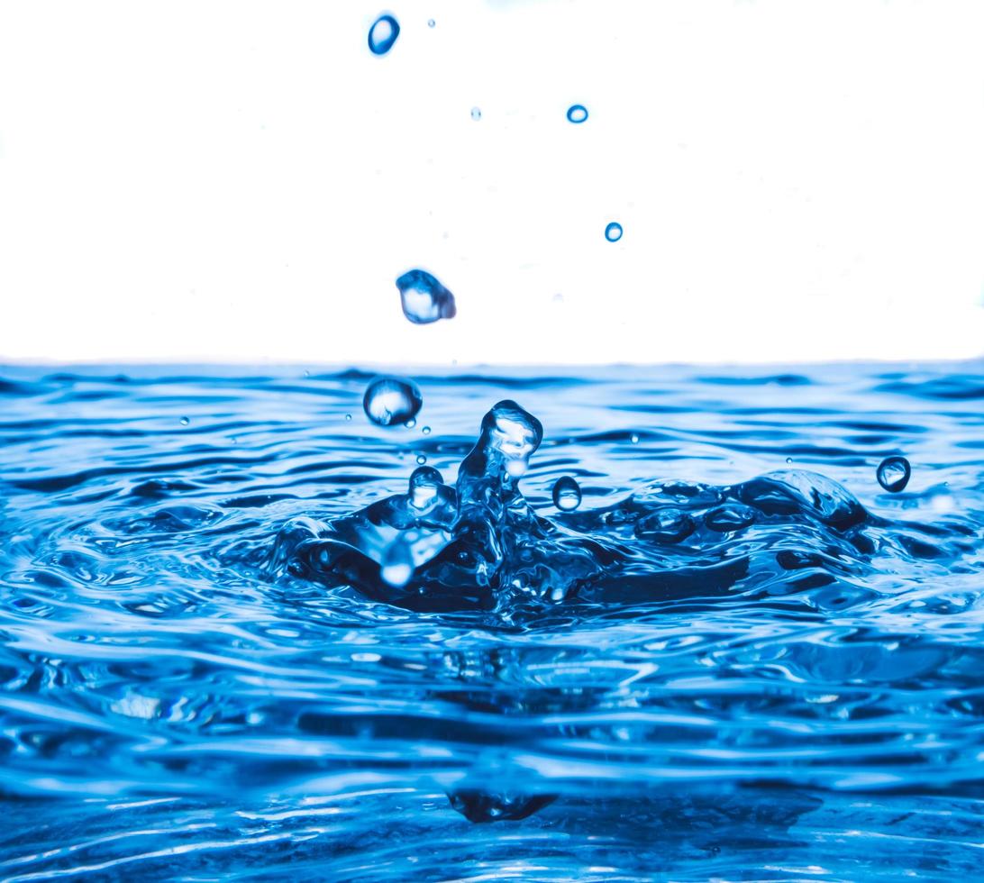 vatten släppa stänk på vatten yta, blå Vinka och bubblor bakgrund. foto