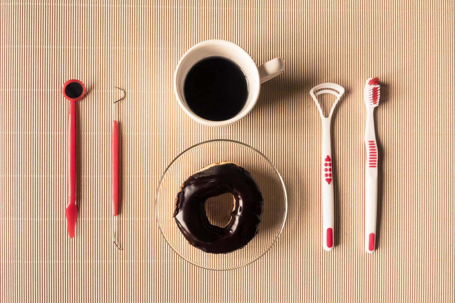 topp se av kaffe kopp med munk och dental verktyg Utrustning på tabell. foto