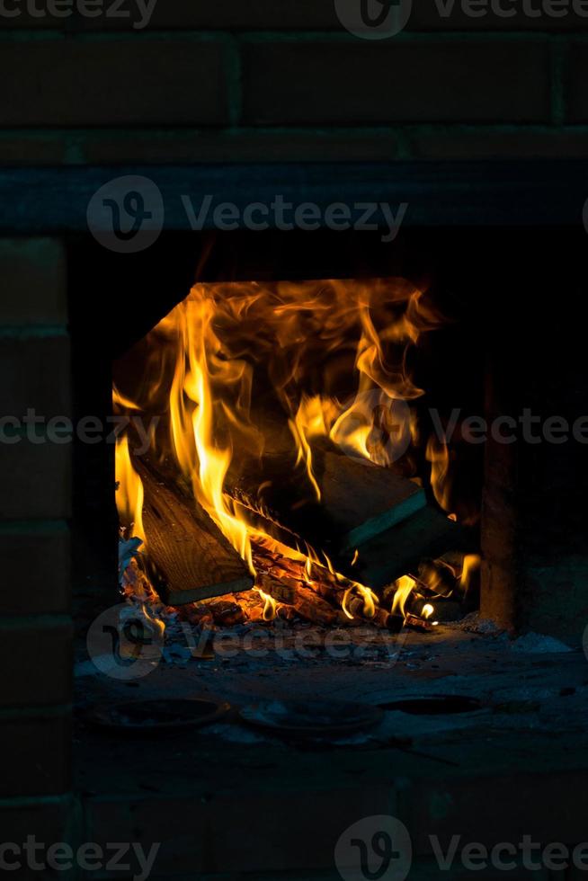 vapen av flamma på brinnande trä i öppen spis. brinnande ved i en ryska spis. foto
