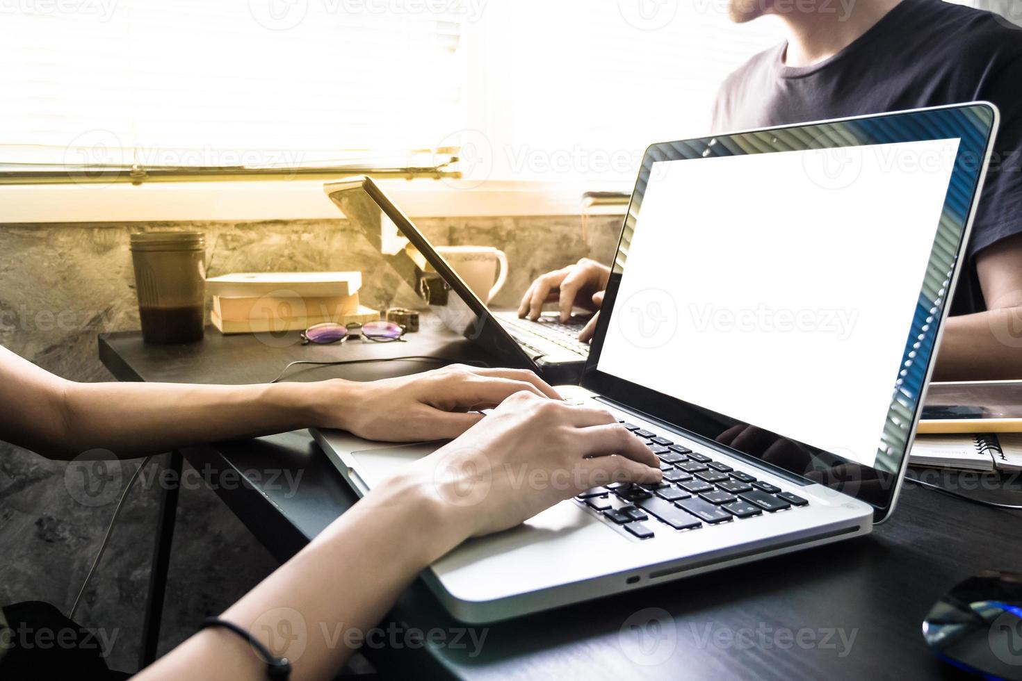 medarbetare arbetssätt på de samma skrivbord, de är använder sig av en bärbar dator med tom skärm, Start upp företag begrepp foto