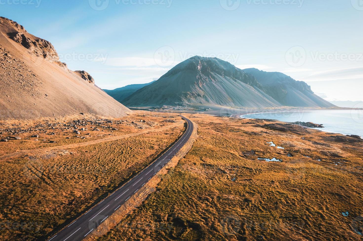 naturskön asfalt väg med berg och gyllene fält på kustlinje i sommar på island foto