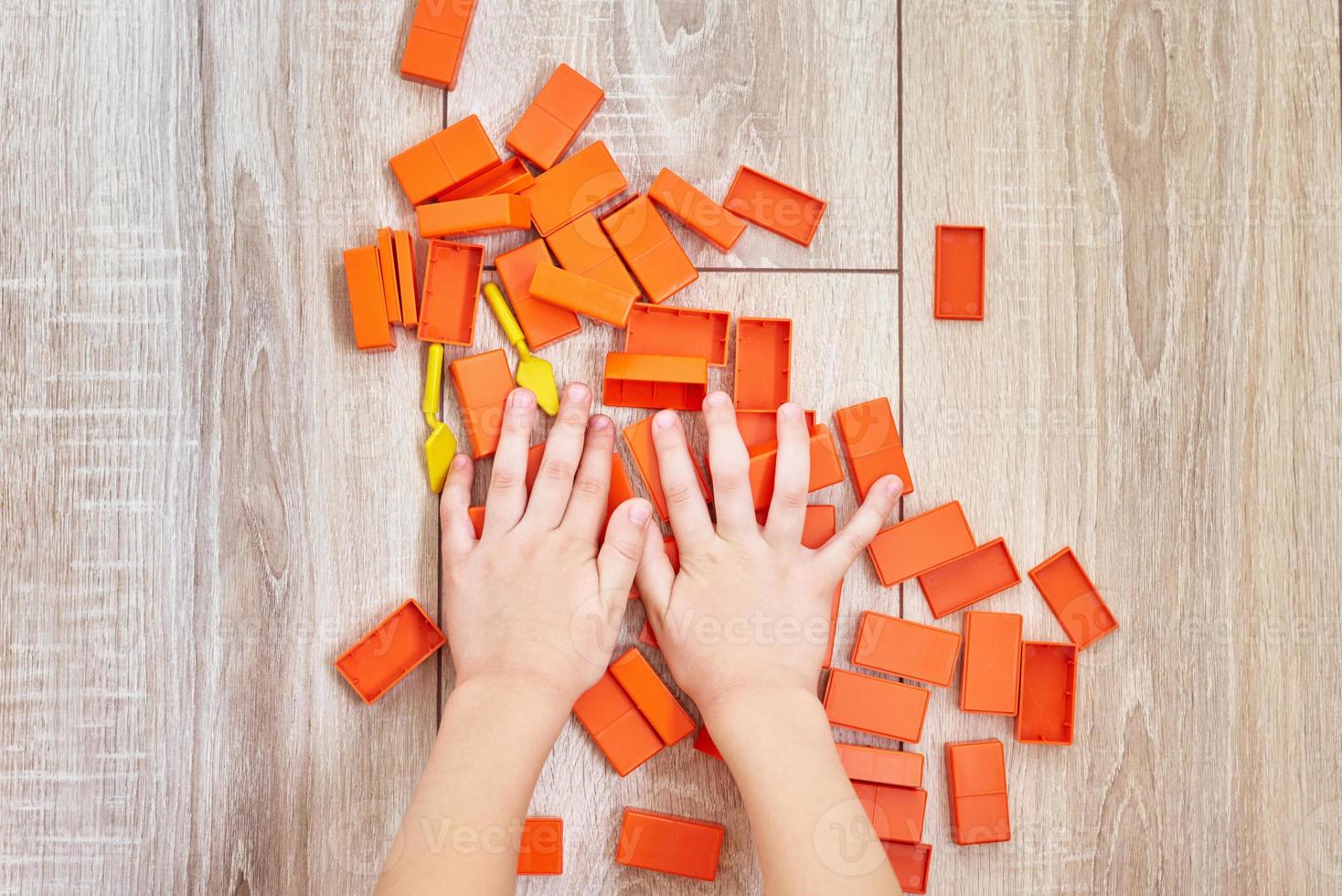 topp se av barn händer spelar med orange leksak tegelstenar foto