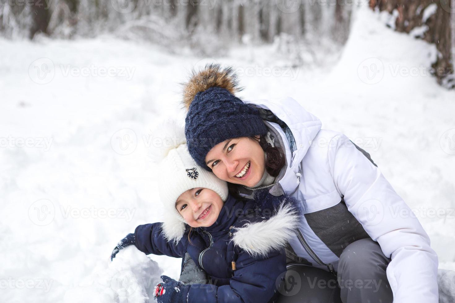 mamma och dotter spela snö spel, bygga en fästning, göra snöbollar. vinter- underhållning utanför, aktiva rekreation, roligt i de kall i värma kläder. utomhus- rekreation, roligt barndom, stark familj foto