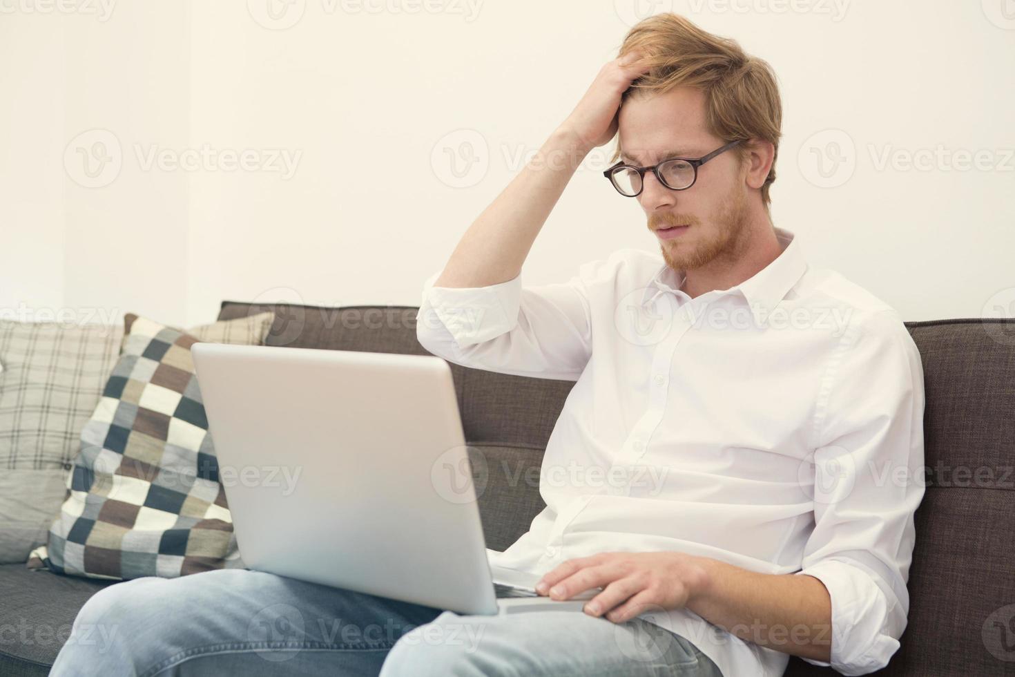 ung man sitter på soffan med laptop foto