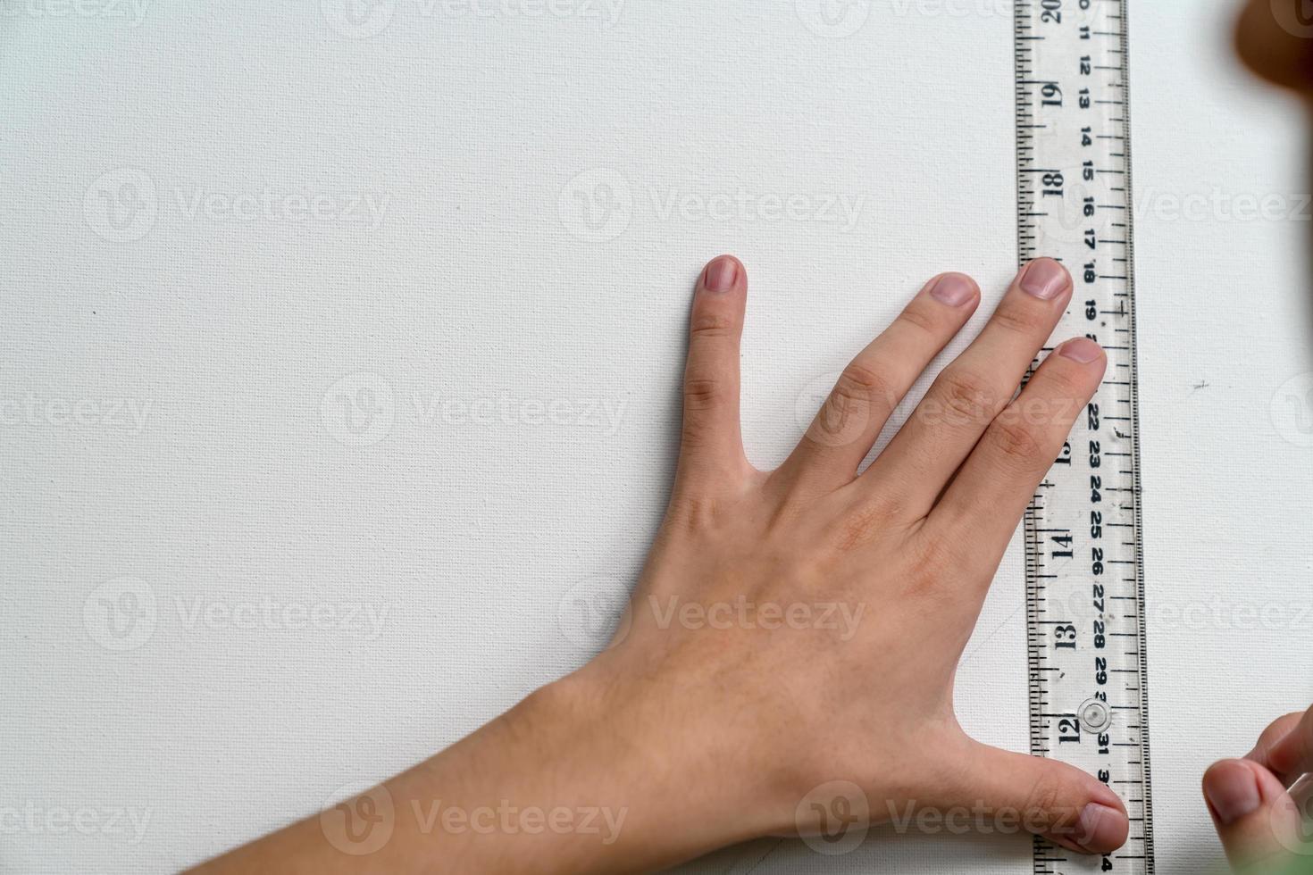 hand som håller linjal och koppling-typ penna med canvas bakgrund foto