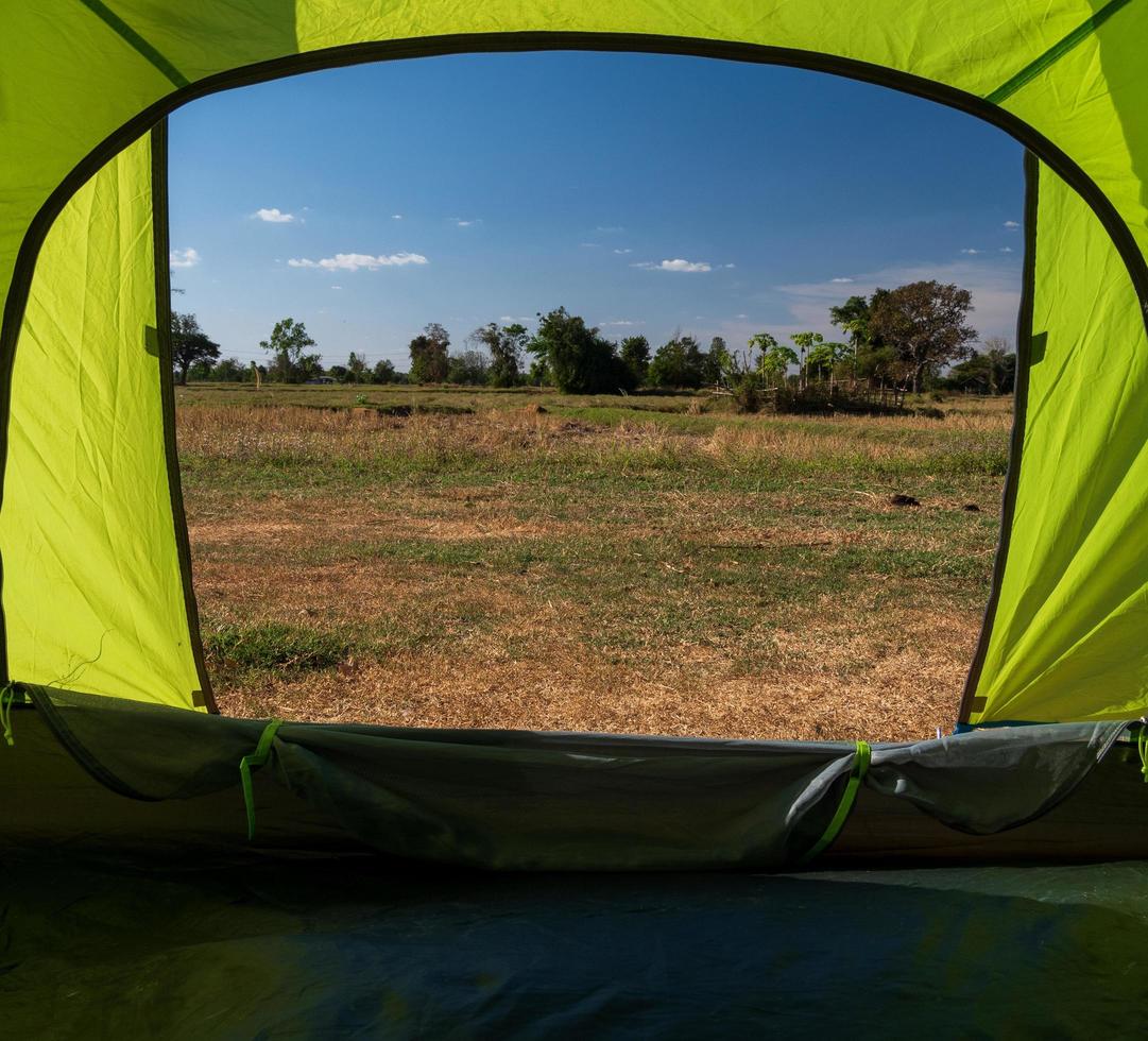 resande grön tält camping utomhus- resa. se från de tält inuti på de blå himmel Sol i de sommar landskap. under de kväll av de dag lämplig för sovande och vilar de kropp foto