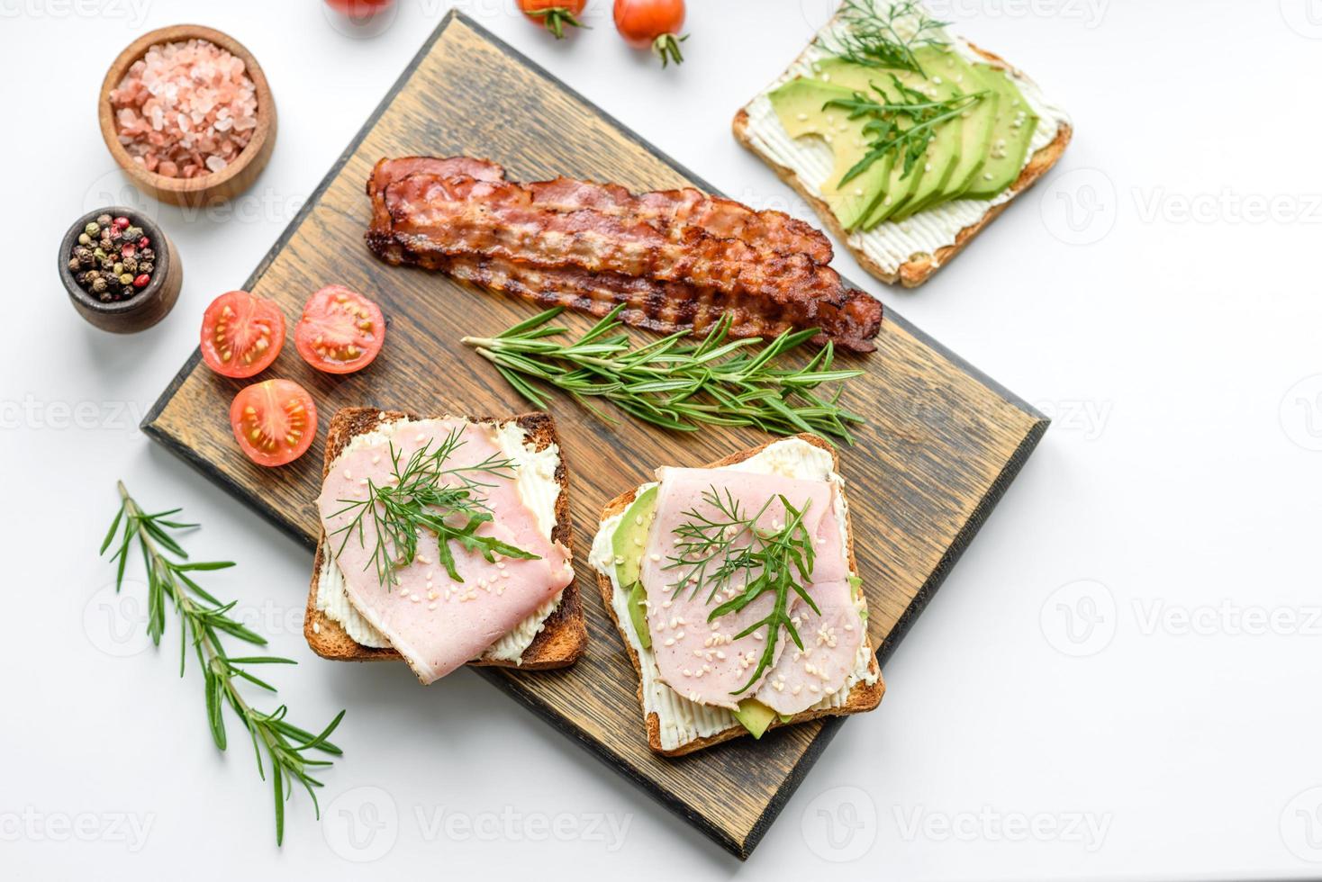 färsk, utsökt skinka, Smör, avokado och sesam frön smörgåsar på en trä- skärande styrelse foto