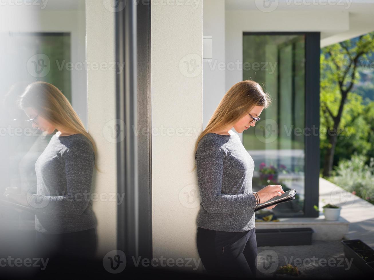 kvinnor använder sig av läsplatta dator i främre av lyx Hem villa foto