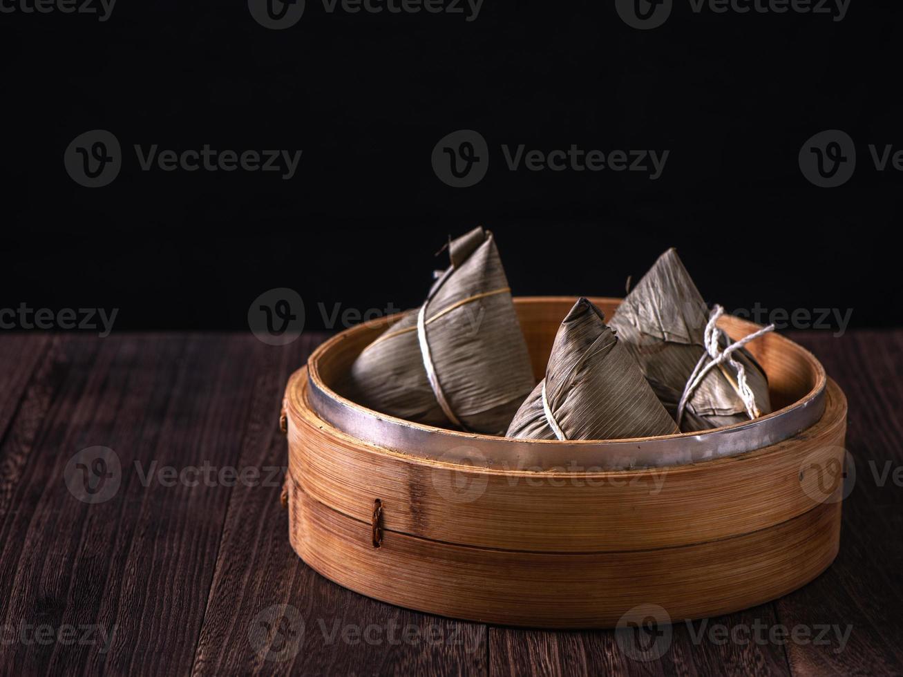 zongzi - kinesisk ris klimp zongzi i en ångkokare på trä- tabell svart retro bakgrund för drake båt festival firande, stänga upp, kopia Plats. foto