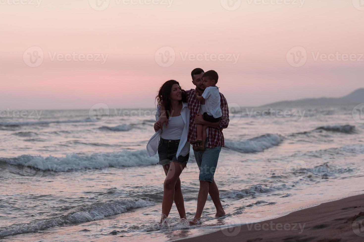 de familj åtnjuter deras semester som de promenad de sandig strand med deras son. selektiv fokus foto