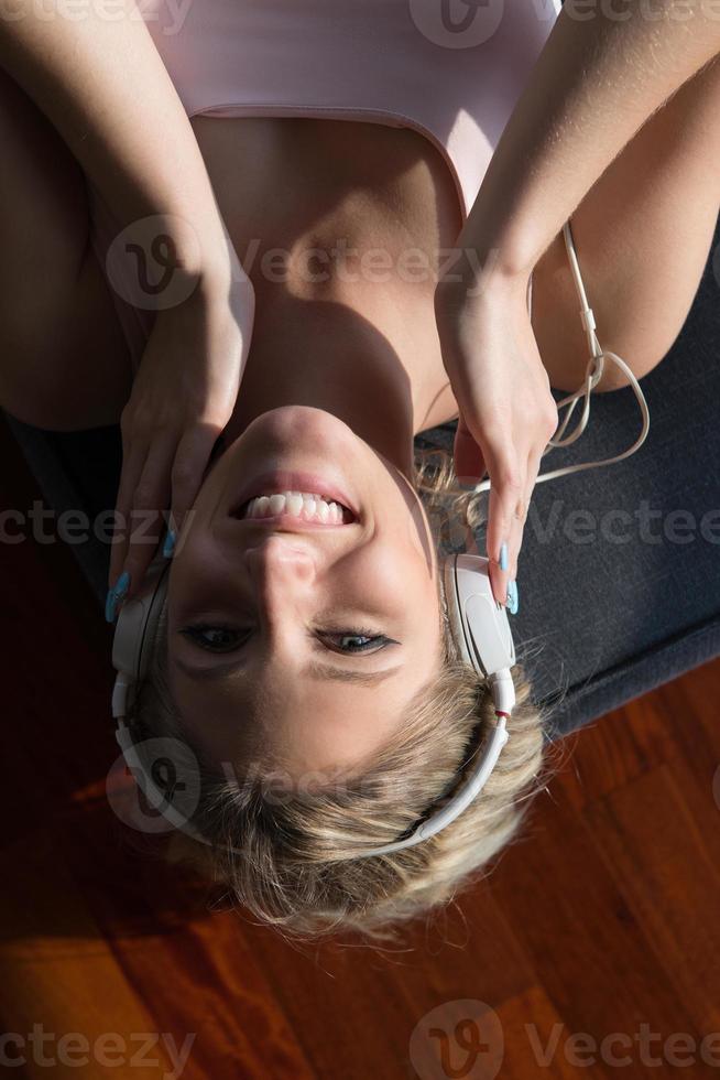härlig blond kvinna lyssnande till musik medan vilar på soffa foto