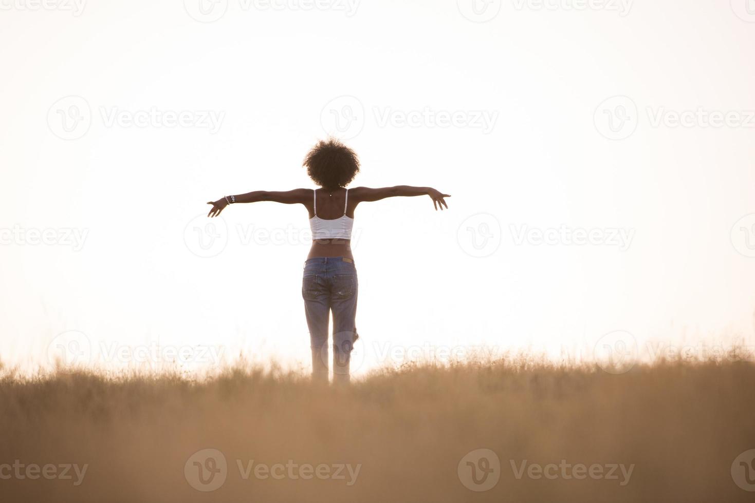 ung svart flicka danser utomhus i en äng foto