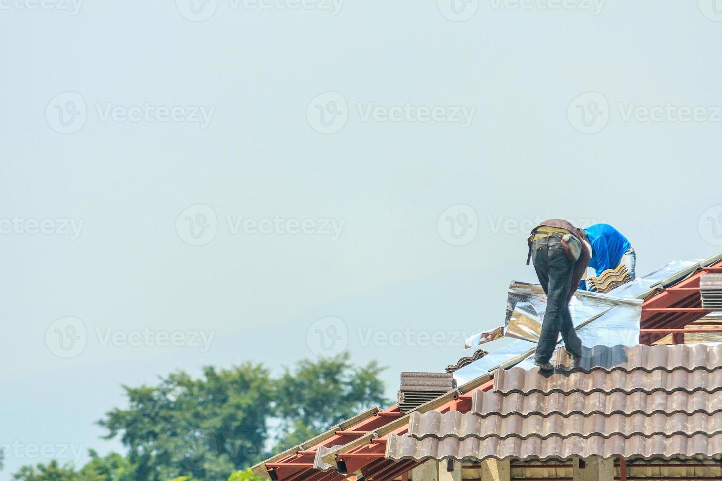byggtäckare som installerar takpannor på husbyggarbetsplatsen foto