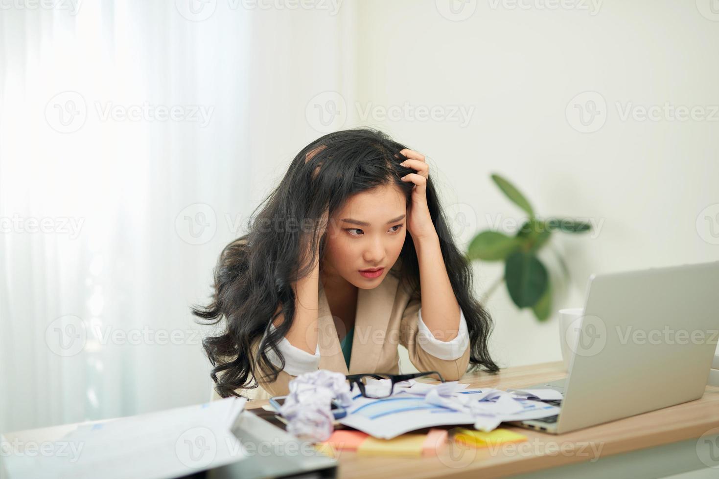 porträtt av ett attraktiv kvinna på de tabell med kopp och bärbar dator, bok, anteckningsbok på Det, gripa tag i henne huvud foto