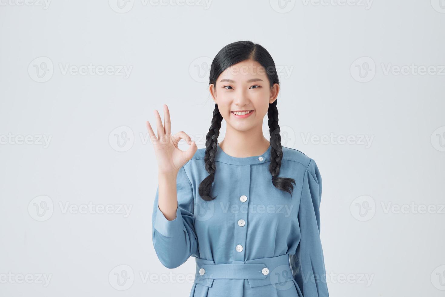 ung asiatisk kvinna som visar en ok hand tecken. foto