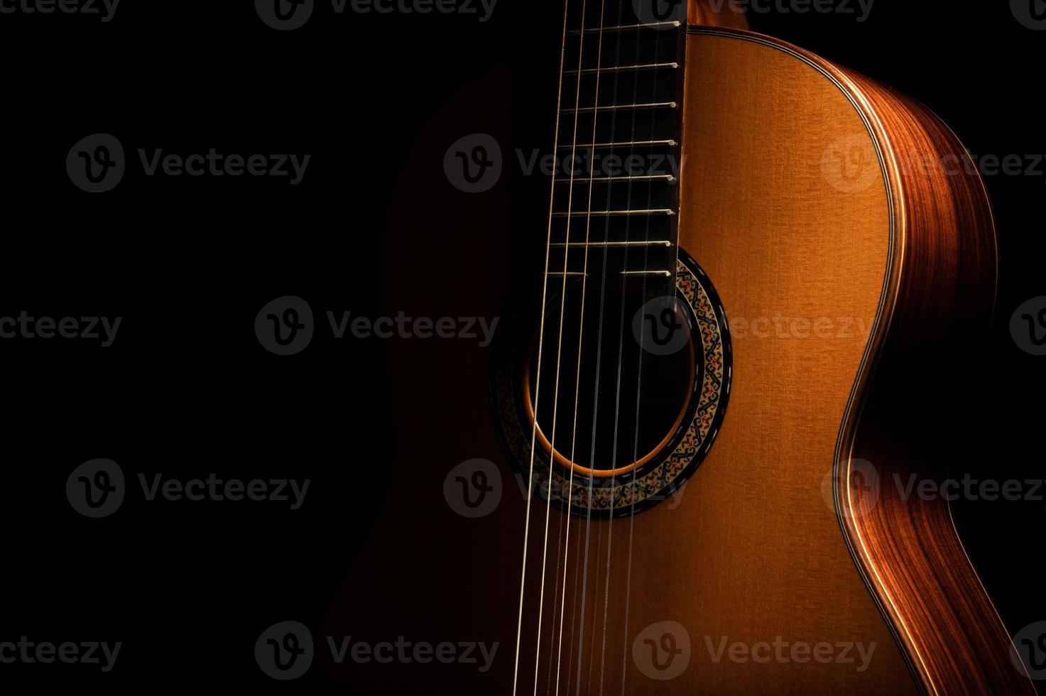klassisk gitarr närbild, dramatiskt upplyst på en svart bakgrund med kopia utrymme foto