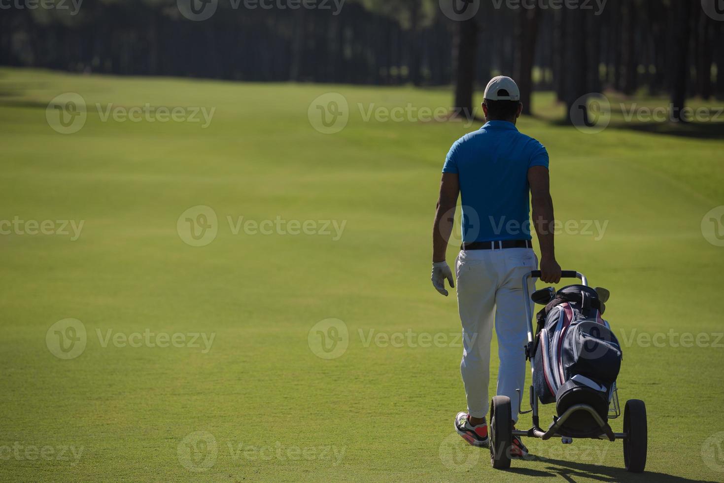 golf spelare gående med hjul väska foto