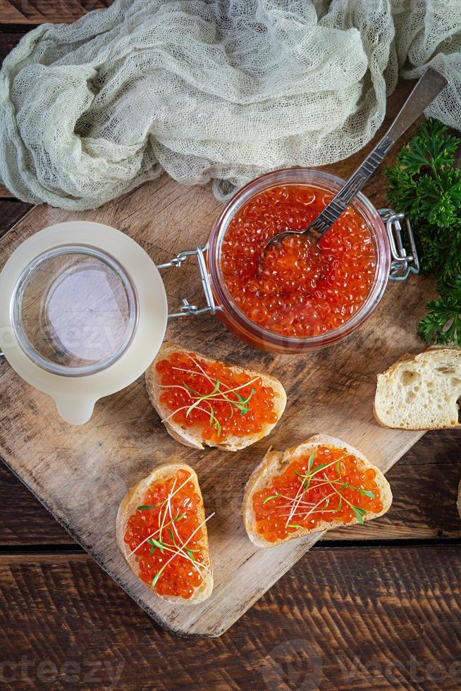 utsökt färsk röd kaviar med baguette skålar på trä- bakgrund. topp se foto