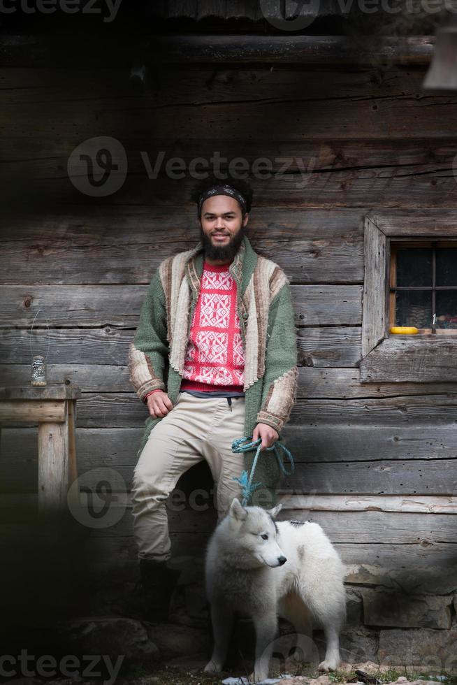 hipster med hund i främre av trä- hus foto