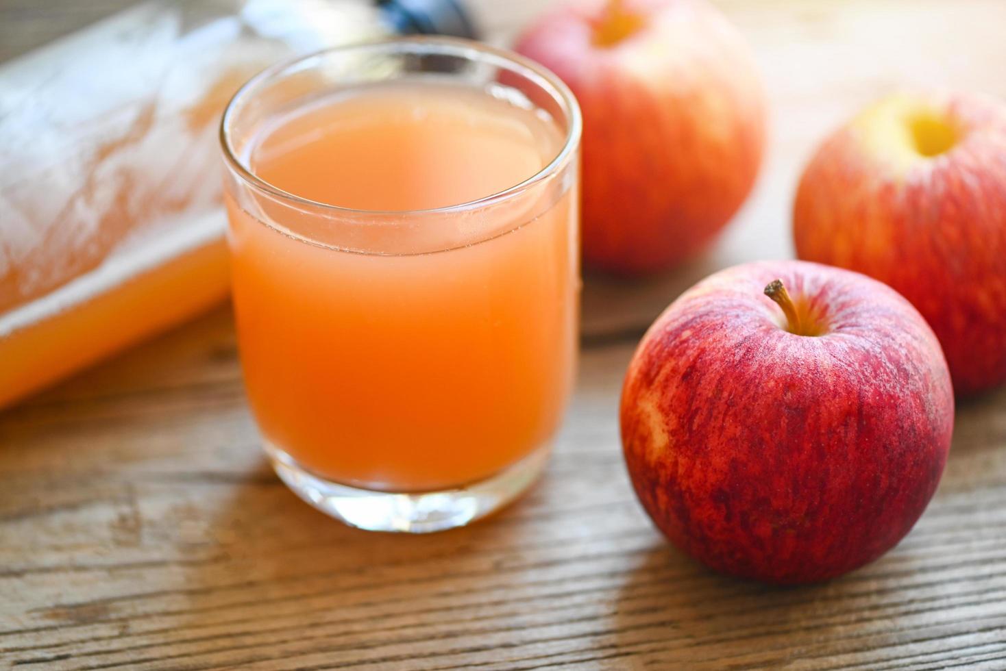 rå och ofiltrerad organisk äpple cider vinäger i glas med äpple frukt på de trä- tabell, äpple cider vinäger naturlig botemedel och botemedel för allmänning hälsa tillstånd foto