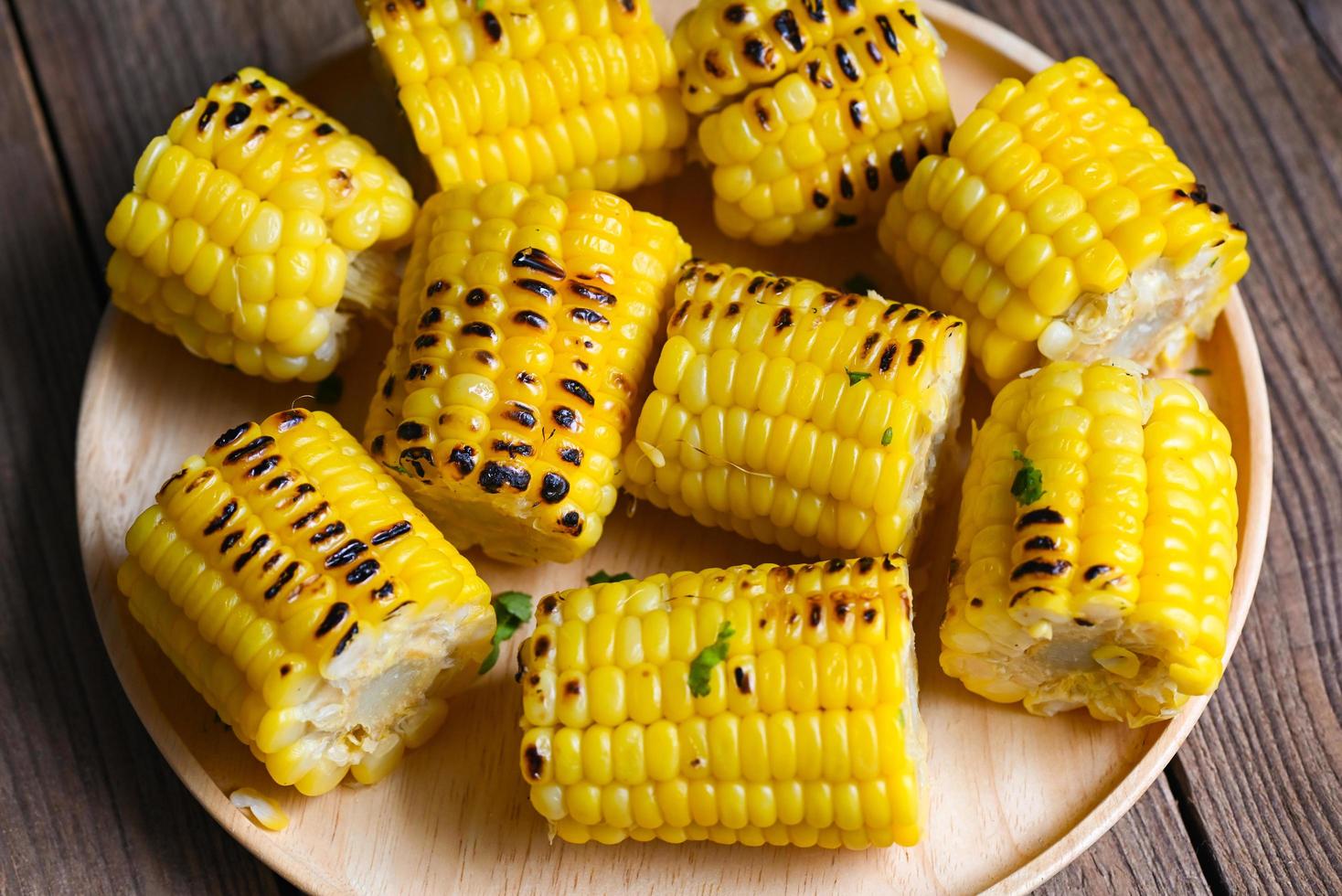 ljuv majs kokta på trä- tallrik bakgrund, mogen majs kolvar grillad söt majs för mat vegan middag eller mellanmål, majs mat foto