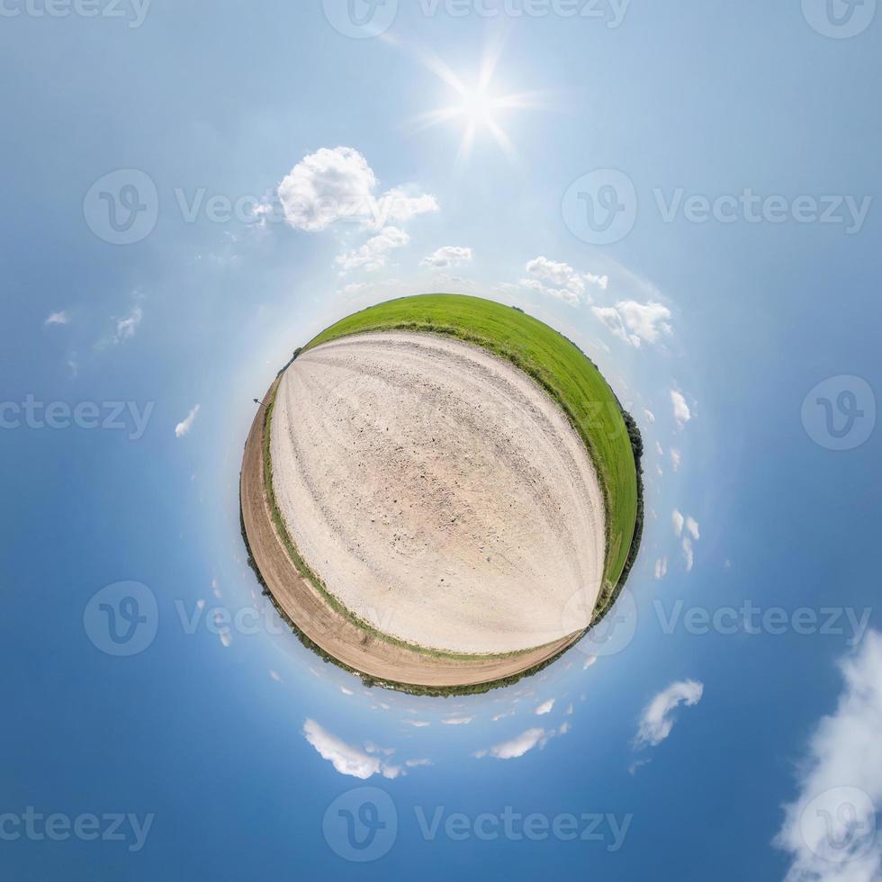 mycket liten planet på grus väg i blå himmel med Sol och skön moln. omvandling av sfärisk panorama 360 grader. sfärisk abstrakt antenn se. krökning av Plats. foto