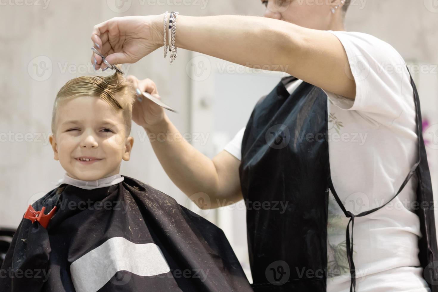 små pojke under frisyr på barberare affär. foto