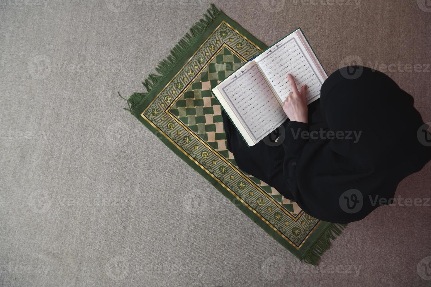 mitten östra kvinna bön- och läsning de helig quran foto