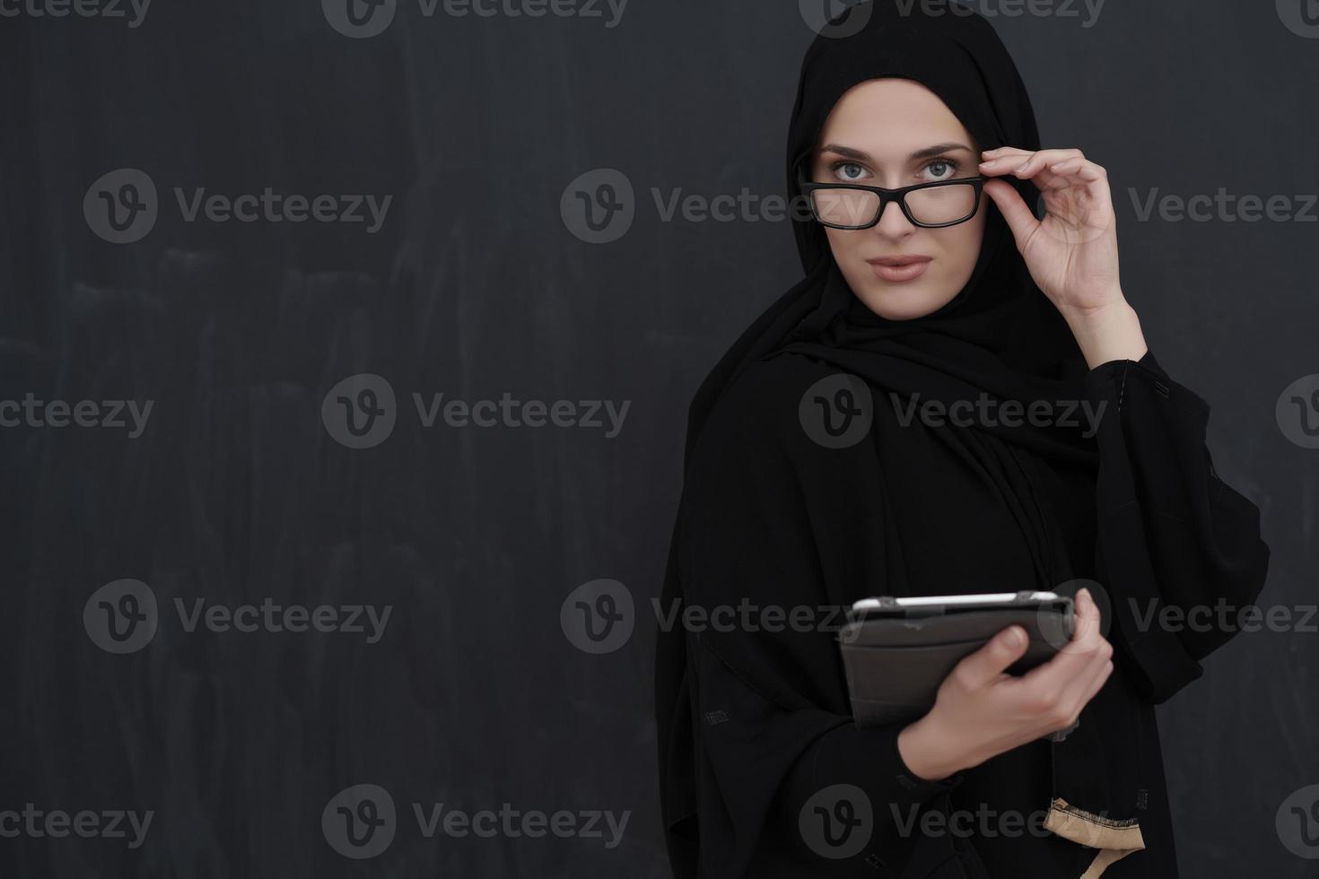 ung arab affärskvinna i traditionell kläder eller abaya innehav läsplatta dator foto