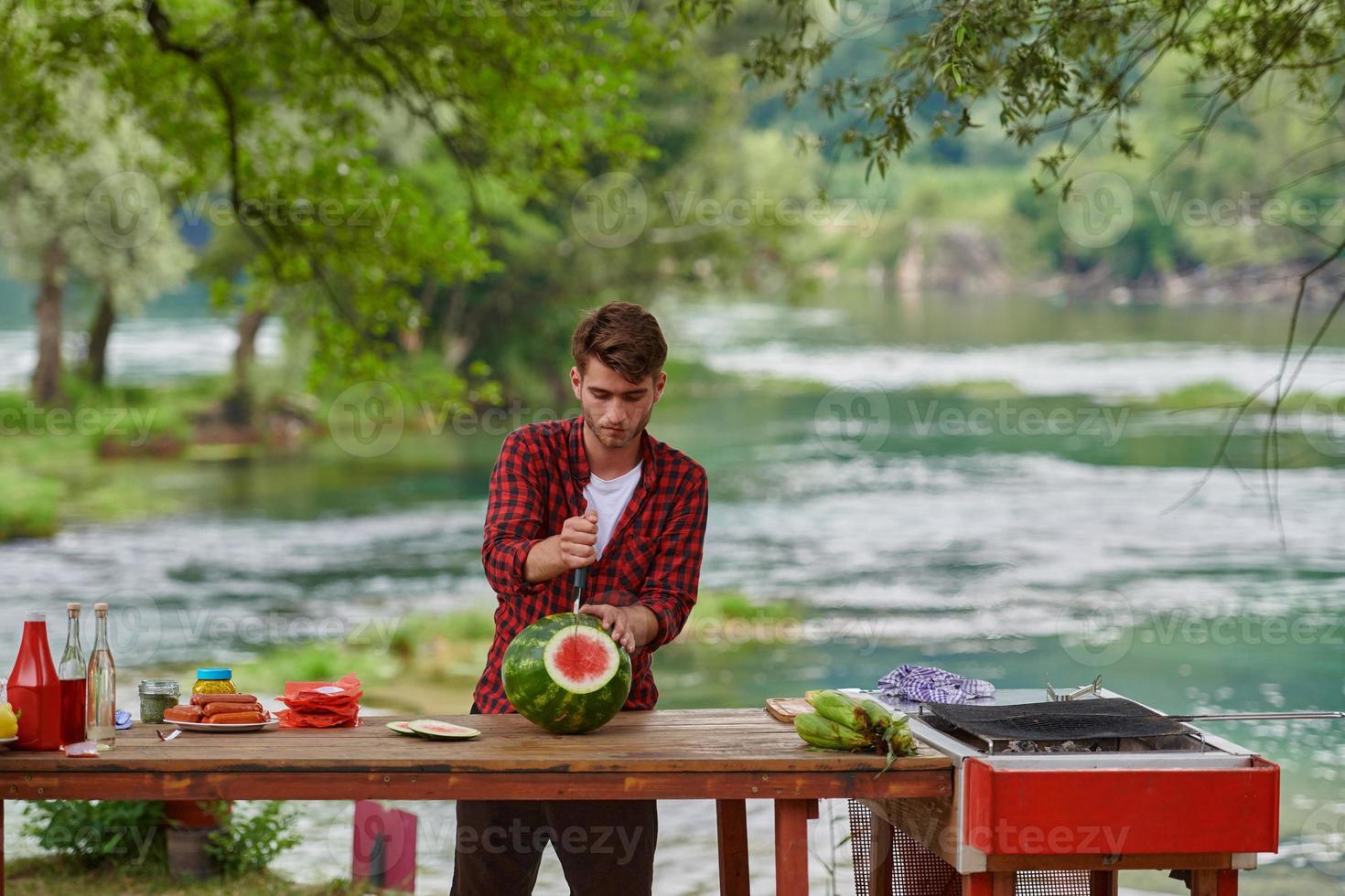 man skärande saftig vattenmelon under utomhus- franska middag fest foto