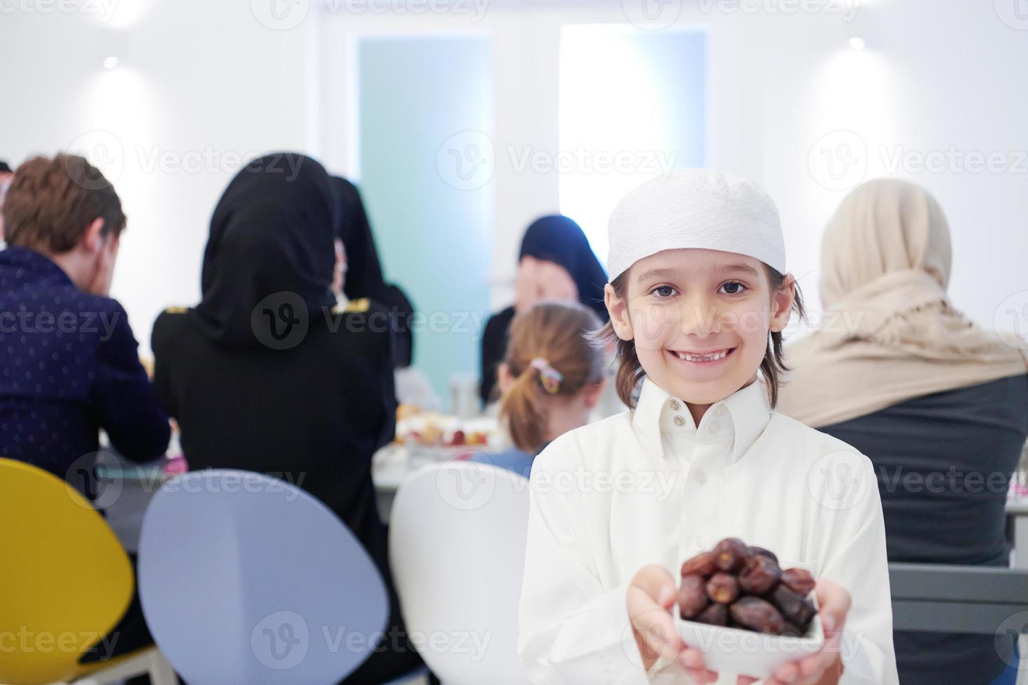 liten muslim pojke innehav en tallrik full av ljuv datum foto